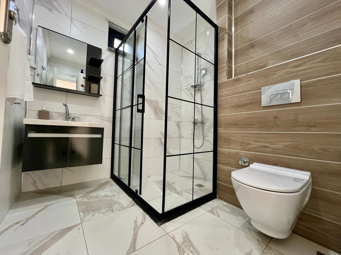 Duşakabinli modern banyo, mermer seramik ve ahşap kaplama